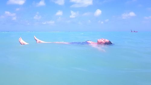 People swimming in sea against sky