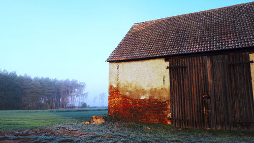 Old wooden house on field against clear sky