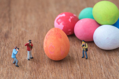 Close-up of male figurines by colorful easter eggs on wooden table