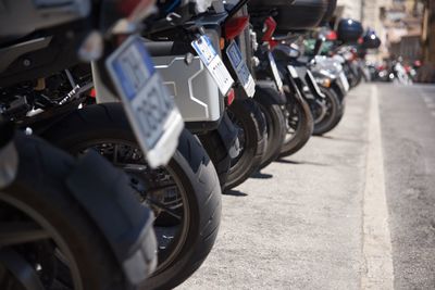 Cropped image of motor scooters parked at parking lot