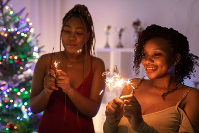 Young woman holding christmas tree at home