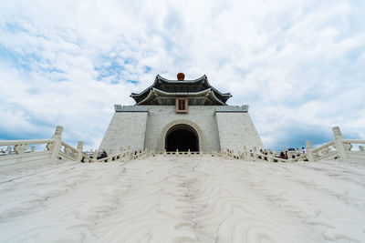 Historic building on beach against cloudy sky