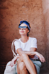 Portrait of young woman sitting against wall