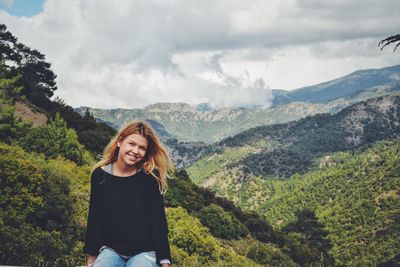 Portrait of woman standing on mountain against sky