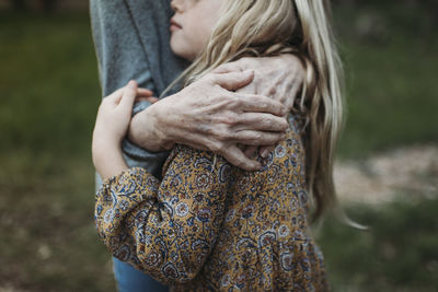 Detail image of young girl being hugged by senior grandmother