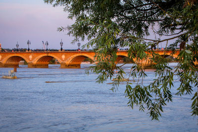 Arch bridge over river against sky