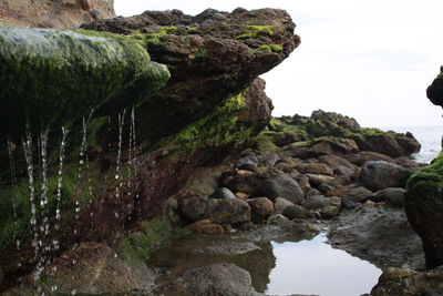 Rocks by sea against sky