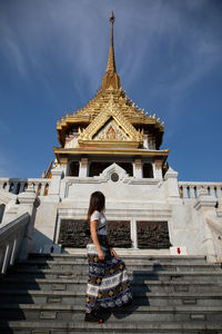 Low angle view of woman outside temple against building