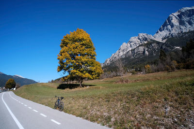 Scenic view of road by mountains against clear blue sky