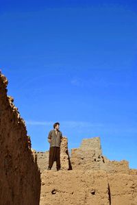 Low angle view of man standing on rock against sky