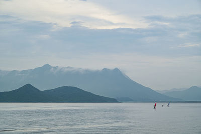 Scenic view of ocean by mountains against sky