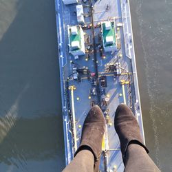 Low section of female wearing suede boots against cargo ship