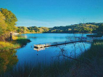 Scenic view of lake against clear blue sky