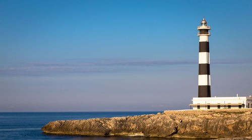 Lighthouse by sea against sky