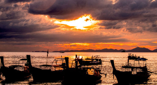 Silhouette boats in sea against sky during sunset