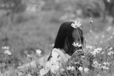 Close-up of woman with flowers blooming on field