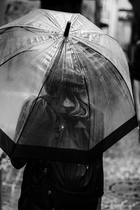 Rear view of woman under umbrella during rainy season