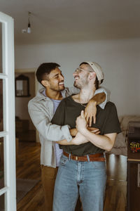 Happy gay couple looking at each other standing in bedroom at home