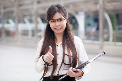 Portrait of young businesswoman gesturing while standing outdoors