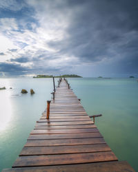 Wooden pier over sea against sky