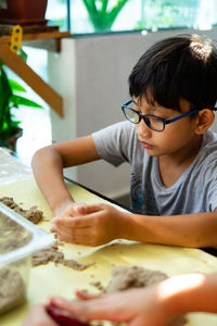 High angle view of boy playing with sand on table