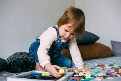 Child plays at home an educational game with a multi-colored magnetic puzzle
