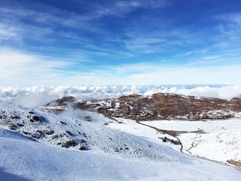 Snow covered landscape against blue sky