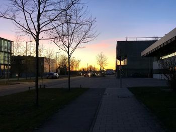 Road by city against clear sky at sunset