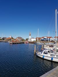 Sailboats moored at harbor against clear blue sky