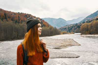 Young woman wearing hat against mountain range against sky