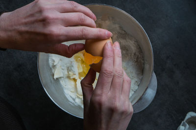 Cropped hand putting egg in flour and butter