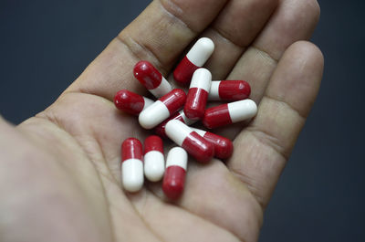 Close-up of human hand holding pills against black background