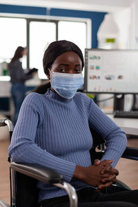 Portrait of young woman wearing mask sitting at hospital