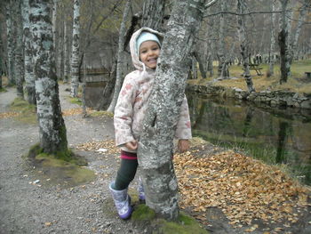 Portrait of happy boy standing on tree trunk