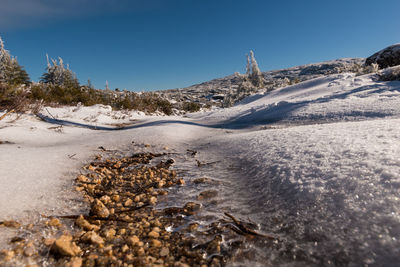 Surface level of snow covered land against sky