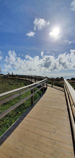 Boardwalk leading towards landscape against sky