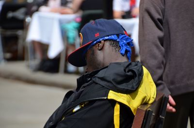 Side view of man wearing cap while sitting on chair