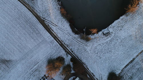 Directly above shot of snow covered road by lake