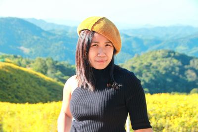 Portrait of smiling young woman standing against mountain