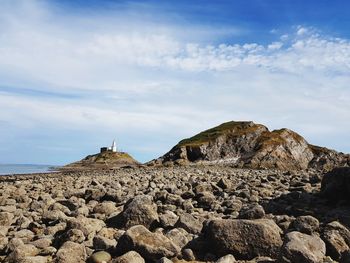 Rock formations on beach against sky