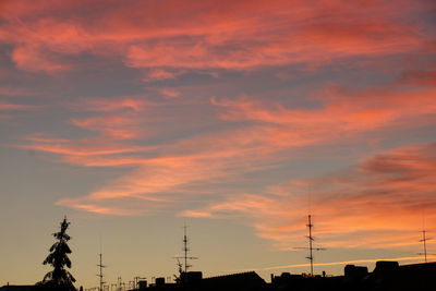 Low angle view of silhouette buildings against orange sky