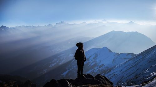 Man standing on snow covered mountain against sky