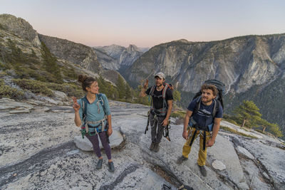 Three hikers at the top of el capitan in yosemite valley at sunset