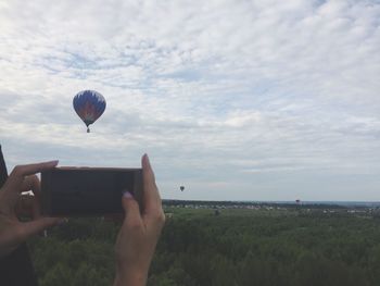 Man holding hot air balloon flying over sea against sky