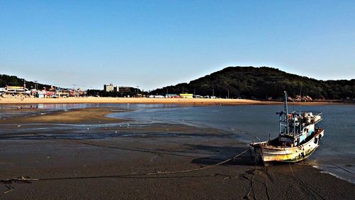 Boats in sea against clear blue sky