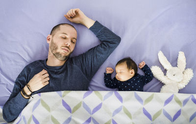 Newborn baby girl,father and a stuffed rabbit sleeping in bed