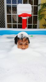 High angle view of boy looking away while bathing in bathtub