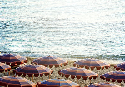 Sun umbrellas open early in the morning on a beach by the sea.