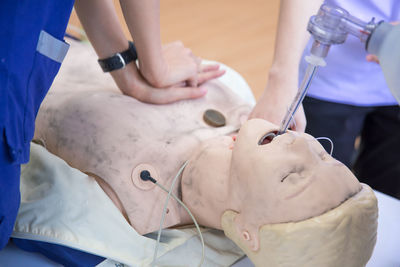 Midsection of paramedic practicing on cpr dummy