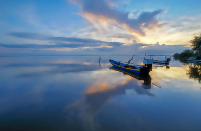 Fishing boat in sea against sky during sunset